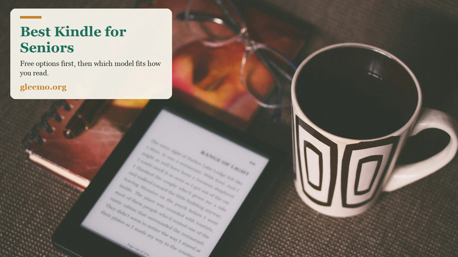 An e-reader showing a page of text beside reading glasses, a notebook and a mug of coffee.